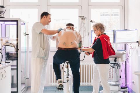 Sportmedizin Untersuchung auf dem Ergometer mit mit Pfleger und Ärztin.
