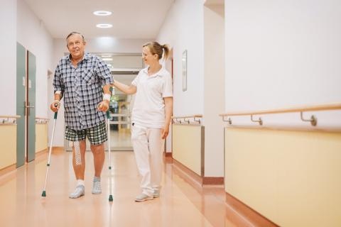 Klinik für Orthopädie am St. Joseph-Stift Dresden, Pflege und Patient an Gehhilfen bei Lauf- und Bewegungstraining nach einer Knie-OP auf der orthopädischen Station im Krankenhaus St. Joseph-Stift Dresden.